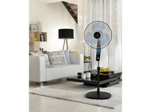 Charger l&#39;image dans la galerie, Un ventilateur sur pied dans un salon, canapé blanc, table basse noire et tapis blanc.
