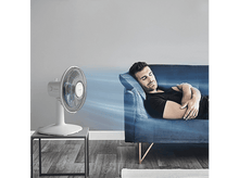 Charger l&#39;image dans la galerie, Un homme dormant sur un canapé bleu, un ventilateur blanc à gauche, soufflant de l&#39;air vers lui.
