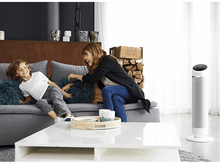 Charger l&#39;image dans la galerie, Une femme et un garçon riant sur un canapé. Un grand ventilateur est à l&#39;arrière-plan à droite.
