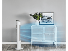 Charger l&#39;image dans la galerie, Un ventilateur blanc souffle de l&#39;air vers une armoire blanche avec une image et un vase. Sol en bois et mur gris en arrière-plan.
