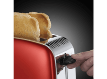 Charger l&#39;image dans la galerie, Un grille-pain rouge avec deux tranches de pain grillé. Une main règle le contrôle de la teinte.
