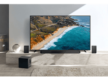 Charger l&#39;image dans la galerie, Une configuration de salon avec une TV, une barre de son, deux enceintes et un caisson de basses. La TV affiche une scène de plage.
