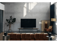 Charger l&#39;image dans la galerie, Un salon moderne avec une grande télévision, une barre de son, deux enceintes et un caisson de basses. Canapé marron et mur en béton.
