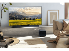 Charger l&#39;image dans la galerie, Une télévision affichant un paysage de montagne au-dessus d&#39;une barre de son et d&#39;un caisson.
