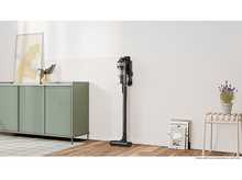 Charger l'image dans la galerie, Un aspirateur noir debout. Il est à côté d'un meuble.
