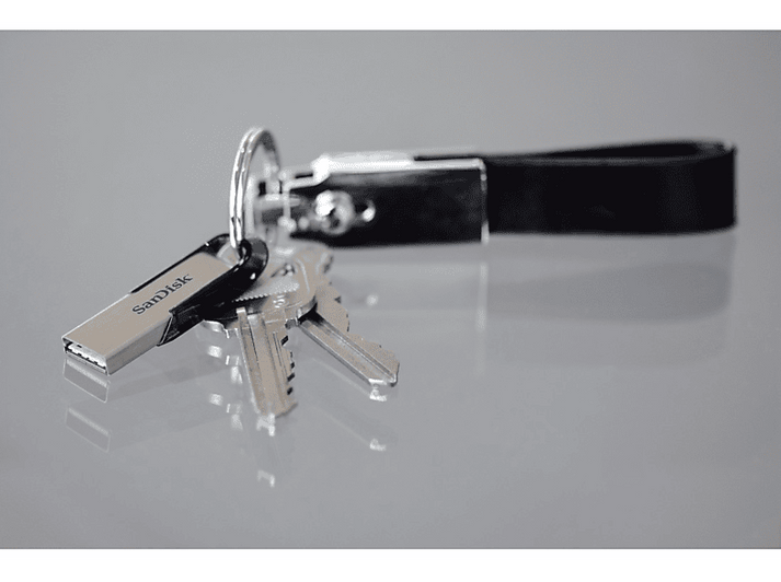 Clés et une clé USB argentée attachées à un porte-clés en cuir noir, posées sur une surface grise.