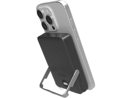 Un iPhone argenté est soutenu par une station de charge noire, indiquant 100 % de charge.