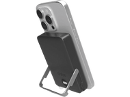 Un iPhone argenté est soutenu par une station de charge noire, indiquant 100 % de charge.