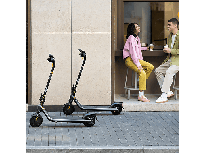 Deux scooters garés sur un trottoir. Un couple est assis à une table en arrière-plan.