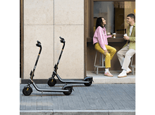 Charger l&#39;image dans la galerie, Deux scooters garés sur un trottoir. Un couple est assis à une table en arrière-plan.
