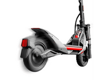 Charger l&#39;image dans la galerie, Une trottinette électrique en mouvement, montrant la roue arrière en rotation et le feu arrière rouge allumé.
