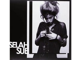 Image en noir et blanc de Selah Sue. Elle porte une chemise sombre et plusieurs colliers, regardant vers le bas. Son nom est imprimé.