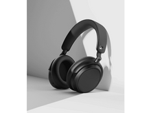 Charger l&#39;image dans la galerie, Casque noir posé sur une surface blanche, fond gris.
