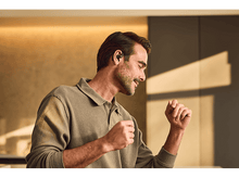 Charger l&#39;image dans la galerie, Homme avec écouteurs, souriant, dansant. Fond: mur aux tons chauds.
