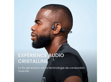Charger l&#39;image dans la galerie, Homme avec casque à conduction osseuse noir, ciel bleu en arrière-plan. Texte : expérience audio cristalline.
