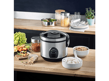 Charger l&#39;image dans la galerie, Cuiseur à riz avec aliments, légumes et ustensiles sur une surface en bois.
