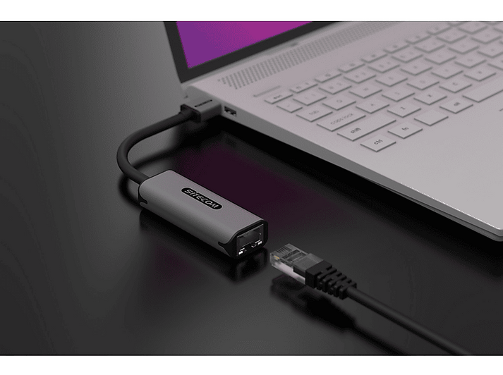 Ordinateur portable connecté à un adaptateur gris via un câble noir. Câble Ethernet branché.