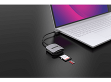 Charger l&#39;image dans la galerie, Un lecteur de carte argenté connecté à un ordinateur portable, avec des cartes SD, sur une table noire.
