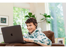 Charger l&#39;image dans la galerie, Un homme souriant avec un casque, travaillant sur un ordinateur portable à la maison.
