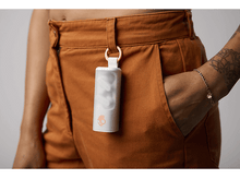 Charger l&#39;image dans la galerie, Main d&#39;une personne tenant un étui avec des écouteurs attachés à une poche de pantalon.
