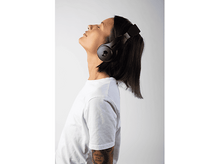 Charger l&#39;image dans la galerie, Femme avec casque noir, chemise blanche, regardant en l&#39;air, fond blanc.
