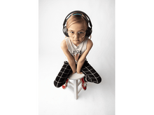 Charger l&#39;image dans la galerie, Une fille avec un casque et des lunettes assise sur un tabouret, regardant en bas.
