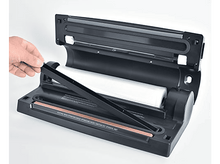 Charger l&#39;image dans la galerie, Machine de scellage sous vide avec un rouleau de plastique à l&#39;intérieur. Une main l&#39;utilise.
