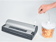 Charger l&#39;image dans la galerie, Une soudeuse sous vide argentée est connectée à un récipient avec des chips. Une main tient le tube.
