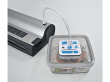 Charger l&#39;image dans la galerie, Scelleuse sous vide avec récipient relié par un tube. Le récipient contient des aliments.
