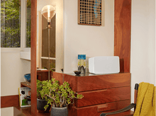 Charger l&#39;image dans la galerie, Étagère en bois avec haut-parleur blanc, décor et plantes. Le miroir reflète la pièce.
