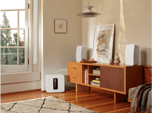 Charger l&#39;image dans la galerie, Un salon élégant avec des enceintes blanches, un caisson de basses et un meuble en bois.
