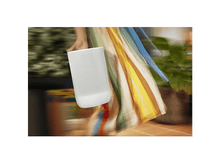 Charger l&#39;image dans la galerie, Un haut-parleur Sonos blanc tenu par une personne avec une robe colorée, fond flou.
