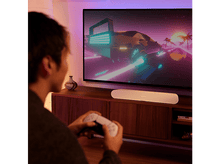 Charger l&#39;image dans la galerie, Une personne tient une manette de jeu blanche, regardant un écran de télévision avec une scène de ville nocturne.
