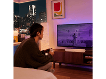 Charger l&#39;image dans la galerie, Homme jouant à un jeu sur TV avec une barre de son blanche.
