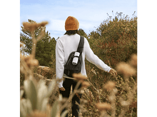 Charger l&#39;image dans la galerie, Une personne randonne avec un sac à dos, un bonnet et un pull blanc.
