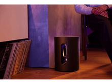 Charger l&#39;image dans la galerie, Caisson de basses près d&#39;un mur et d&#39;une personne assise. L&#39;appareil est de forme ronde.
