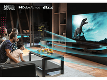 Charger l&#39;image dans la galerie, Une famille regarde la télévision avec une scène de dinosaures et un effet d&#39;onde sonore.
