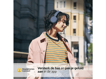 Charger l&#39;image dans la galerie, Une femme écoutant de la musique avec un casque bleu, portant une veste rose.
