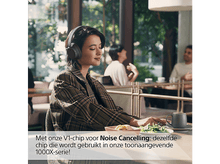 Charger l&#39;image dans la galerie, Femme avec casque dans un café. Café et salade sur la table. Autres personnes floues en arrière-plan.
