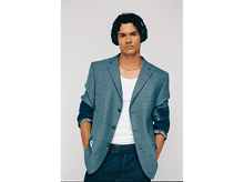 Charger l&#39;image dans la galerie, Un homme portant un casque, un blazer gris avec des accents en jean, une chemise blanche et un jean foncé. Il a une chaîne en or et les mains dans les poches.
