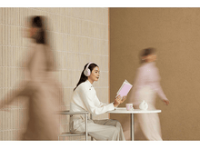 Charger l&#39;image dans la galerie, Femme avec un casque rose lisant un livre, personnes floues.
