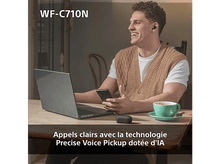 Charger l&#39;image dans la galerie, Un homme souriant avec des écouteurs, travaillant sur un ordinateur portable et tenant un téléphone. Une tasse et un étui sur la table.
