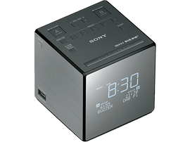 Un réveil Sony gris. Il est carré avec un affichage numérique qui affiche 8h30.