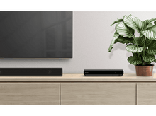 Charger l&#39;image dans la galerie, Un téléviseur, une barre de son et un lecteur Blu-ray sur un meuble en bois. Une plante en pot à droite.
