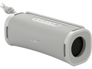 Un haut-parleur portable gris avec un cordon blanc, incliné sur un fond noir.