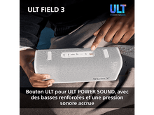 Charger l&#39;image dans la galerie, Haut-parleur blanc et gris. La main d&#39;une personne appuie sur un bouton du haut-parleur. Texte en français.
