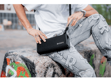 Charger l&#39;image dans la galerie, Homme tenant un sac d&#39;enceinte noir avec la marque Sony blanche.
