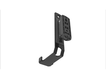 Charger l&#39;image dans la galerie, Un support métallique noir avec un mécanisme de fixation pour un appareil, sur fond blanc.
