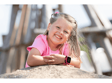 Charger l&#39;image dans la galerie, Fille souriante avec une montre rose sur une pierre, regardant la caméra.
