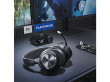 Charger l&#39;image dans la galerie, Casque gaming noir avec micro, sur un bureau avec téléphone et écran.
